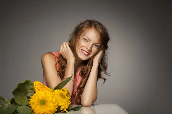 Rödhårig ung kvinna med gula blommor — Stockfoto