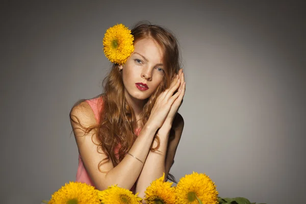 Rothaarige junge Frau mit gelben Blumen — Stockfoto