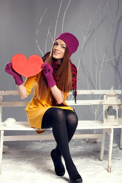 Woman holding heart while sitting on a bench — Stock Photo, Image