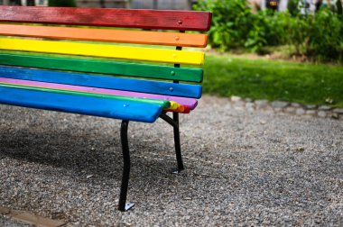 LGBTQ rainbow painted  bench in a park on sunny spring day as a support of gay community in city of Zagreb, Croatia