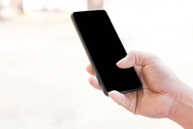 İş dünyası ya da sosyal medya internet iletişimi için fotokopi alanı olan siyah ekranda telefondaki bulanık arkaplanlı akıllı telefonu tutan adamın görüntüsünü kapat