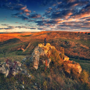 Dağlarda yürüyüş yapan bir kadın kayalıklarda yürüyor. Renkli sonbahar gündoğumu