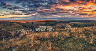 Dağlarda yürüyüş yapan bir kadın kayalıklarda yürüyor. Renkli sonbahar gündoğumu