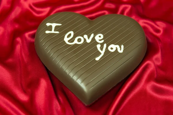 Chocolate heart on red satin — Stock Photo, Image