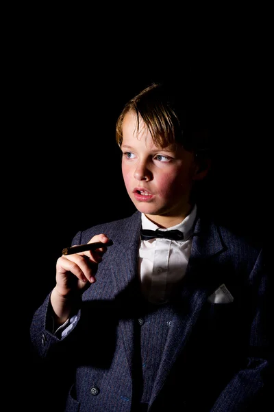 Junge im Anzug, eine Zigarre in der Hand. Unauffälliges Image. — Stockbild Smoking-Junge — Stockfoto