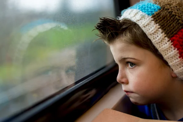 Junge starrt durch Fenster — Stockfoto