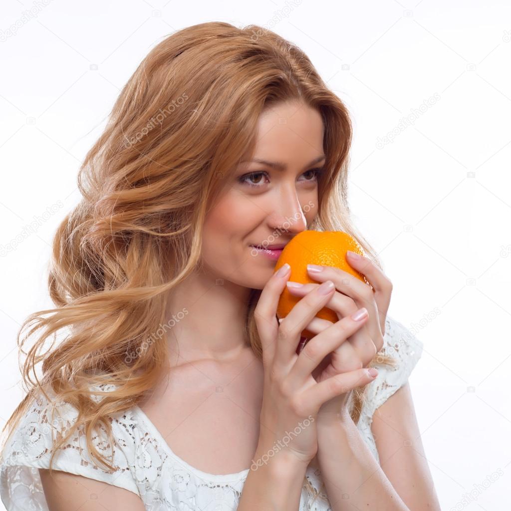 glamorous portrait of a young woman sniffing an orange