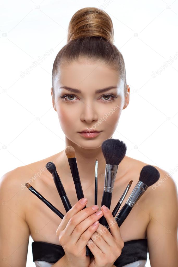 portrait of a beautiful young woman with make-up brushes in hand