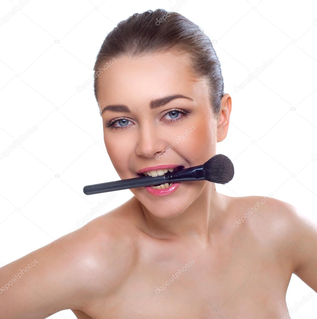 Portrait of a beautiful young woman with a makeup brush
