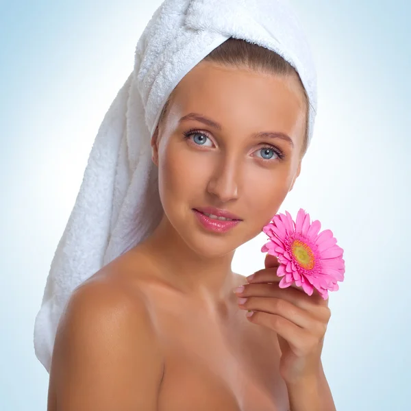 Piękna młoda kobieta uśmiechający się z ręcznikiem na głowie i kwiat — Zdjęcie stockowe
