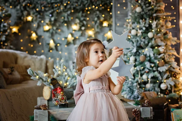 Vacker Liten Flicka Håller Trästjärnor Händerna Bakgrund Med Julpynt Och — Stockfoto