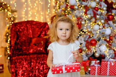 Noel ağacı ve çelenk ışıkları olan bir odada kırmızı elbiseli, kıvırcık sarışın bir kızın büyük bir portresi..