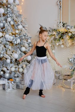 Süslü bir Noel ağacının yanında pofuduk beyaz etekli güzel bir balerin.