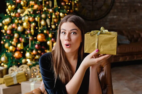 Young Brunette Woman Holds Gift Her Hands Background Golden Christmas — Stock Photo, Image