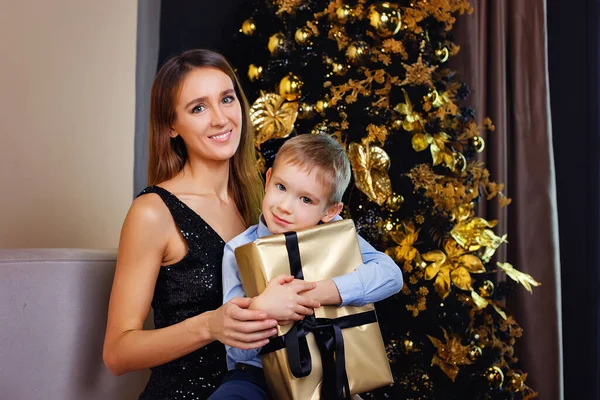 Szczęśliwa Matka Syn Świątecznych Ubraniach Choince Prezentem Złotym Opakowaniu Uśmiechają — Zdjęcie stockowe