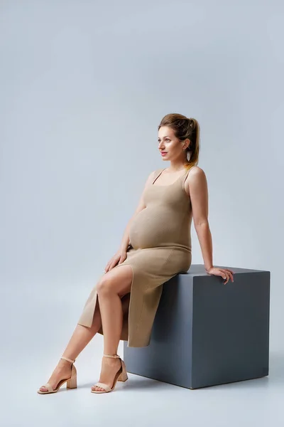 Portrait Beautiful Young Pregnant Woman Beige Dress Sitting Studio Gray — Foto Stock