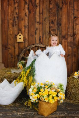 Küçük bir kız büyük bir Paskalya yumurtasının üzerinde oturuyor. Çiçek ve samanla büyük bir yumurtanın şenlikli dekorasyonu. Paskalya konsepti.
