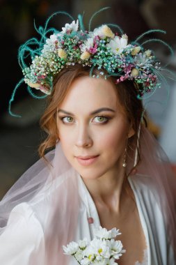 Düğün saç stili ve makyajlı duvağı ve çiçek çelengi olan güzel bir gelinin büyük portresi. Gelinin sabahı.