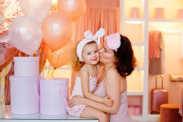 Pembe pijamalı genç bir anne ve kız soyunma odasında sarılıyorlar..