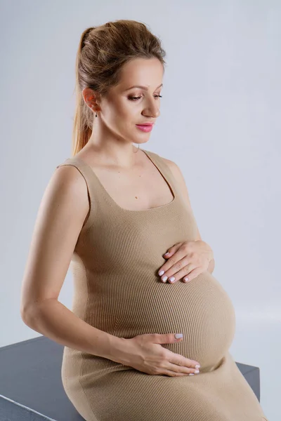Detailní Portrét Těhotné Ženy Béžových Šatech Objímající Její Břicho Oběma — Stock fotografie