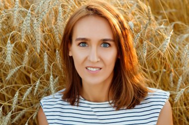 Gün batımında buğday tarlasında güzel bir esmer kadın. Çavdar ekmeğinin arka planında gülümseyen güzel bir genç kadın..