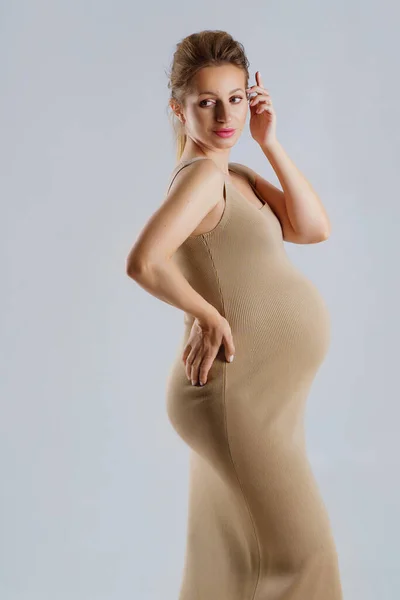 Retrato Estúdio Uma Mulher Grávida Jovem Elegante Vestido Bege Fundo — Fotografia de Stock