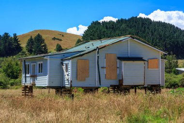 Terk edilmiş, tahta kaplı bir çiftlik evi, kaldırılması için bloklara asılmış. Fotoğraf: Yeni Zelanda