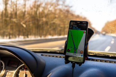 Arabadaki akıllı telefonlarda waze haritaları uygulaması kullanılıyor. Sürücü, Romanya 'nın Bükreş kentindeki trafikte doğru rotayı göstermek için harita uygulaması kullanıyor.