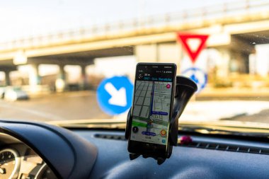 Arabadaki akıllı telefonlarda waze haritaları uygulaması kullanılıyor. Sürücü, Romanya 'nın Bükreş kentindeki trafikte doğru rotayı göstermek için harita uygulaması kullanıyor.