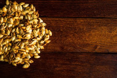 Ahşap masada kavrulmuş tuzlu kabak çekirdeği.