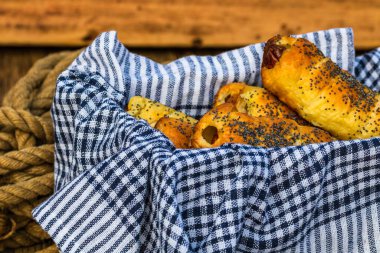 Hamurda pişmiş sosisler tuzlu ve haşhaş tohumları serpiştirilmiş, kırsal bir kompozisyonda. Sosisli börek, lezzetli ev yapımı hamur işleri..