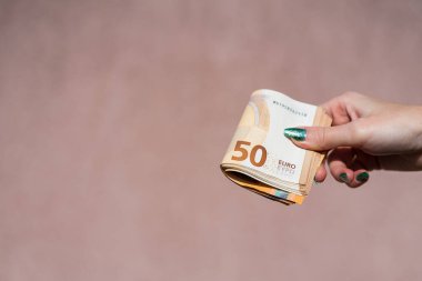 Avro parasını gösteren ve bahşiş, maaş gibi para veren ya da alan el ele tutuşmalar. 50 Avro banknotları izole edilmiş. Zengin iş adamları kavramı, para biriktirmek ya da harcamak.