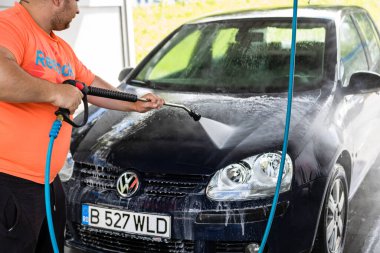 Otomobil yıkama istasyonunda araba yıkama ve temizleme. Romanya 'nın Bükreş kentinde yüksek basınçlı su kullanan araba yıkama, 2021