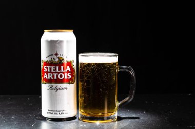 Bir kutu Stella Artois birası ve arka planda bira bardağı. Romanya 'nın Bükreş kentinde 2021 yılında çekilen illüstrasyon fotoğrafı