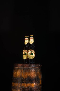 Bir şişe Birra Moretti birası. Ahşap fıçının üzerinde, koyu arkaplanlı. Bükreş, Romanya, 2021