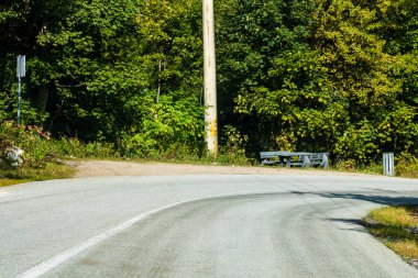 Güneşli bir günde ağaçların arasındaki dağ yolunun arabasının ön camından bak..