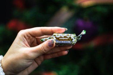 Noel ağacının önünde çikolatalı şekerlemeleri tutarken. Romanya 'nın Bükreş kentinde Noel için Şekerler, 2021