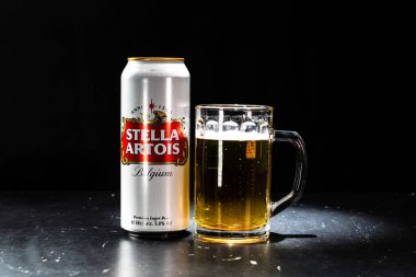 Bir kutu Stella Artois birası ve arka planda bira bardağı. Romanya 'nın Bükreş kentinde 2021 yılında çekilen illüstrasyon fotoğrafı