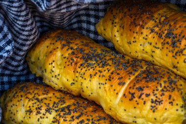 Hamurda pişmiş sosisler tuzlu ve haşhaş tohumları serpiştirilmiş, kırsal bir kompozisyonda. Sosisli börek, lezzetli ev yapımı hamur işleri..
