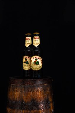 Bir şişe Birra Moretti birası. Ahşap fıçının üzerinde, koyu arkaplanlı. Bükreş, Romanya, 2021