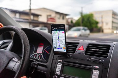 Araba gösterge panelindeki akıllı telefondaki waze haritaları uygulaması, sürücü, şehir trafiğinde doğru yolu göstermek için harita uygulaması kullanıyor. Bükreş, Romanya, 2020.