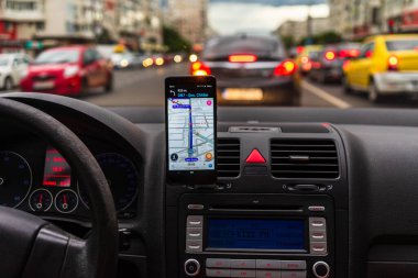 Araba gösterge panelindeki akıllı telefondaki waze haritaları uygulaması, sürücü, şehir trafiğinde doğru yolu göstermek için harita uygulaması kullanıyor. Bükreş, Romanya, 2020.