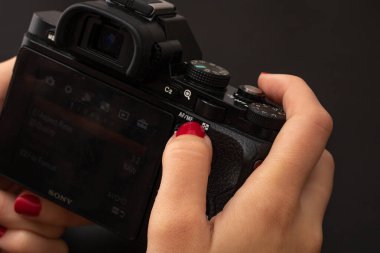 Dijital fotoğraf makinesi kullanan bir el. Bükreş, Romanya, 2021 'de siyah ahşap arka planda aynasız fotoğraf makinesi