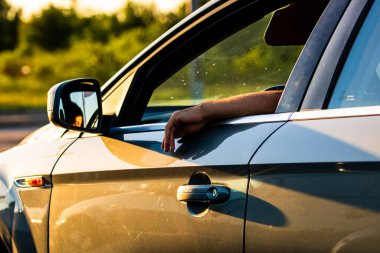 Sürücü, açık pencereli, arabanın kapısında el ele tutuşup trafik konseptini bekliyor. Bükreş, Romanya, 2021