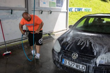 Otomobil yıkama istasyonunda araba yıkama ve temizleme. Romanya 'nın Bükreş kentinde yüksek basınçlı su kullanan araba yıkama, 2021