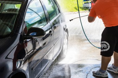 Otomobil yıkama istasyonunda araba yıkama ve temizleme. Romanya 'nın Bükreş kentinde yüksek basınçlı su kullanan araba yıkama, 2021
