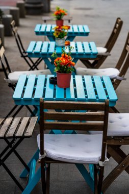 Romanya 'nın Bükreş kentindeki bir açık hava restoranında boş sandalyeli boş masaları kapat, 2021