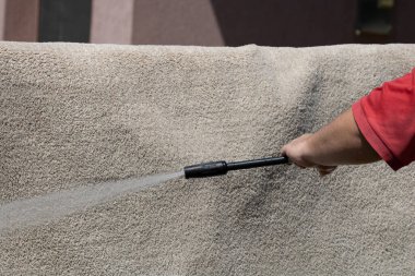 Yüksek basınçlı yıkamalı halılar. Yüksek basınçlı suyu yıkamak için halıyı silahla temizlemek.