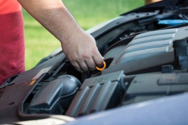 Araba tamircisi motor yağı seviyesini kontrol ediyor.