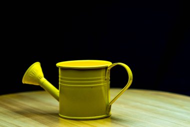 Tahta masadaki sarı sulama kutusu.